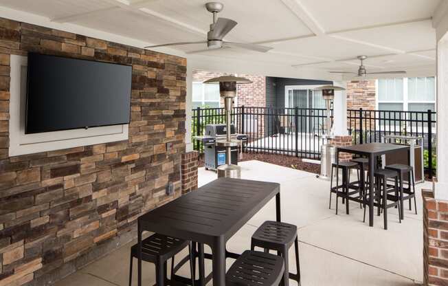 a patio with tables and chairs and a television on the wall