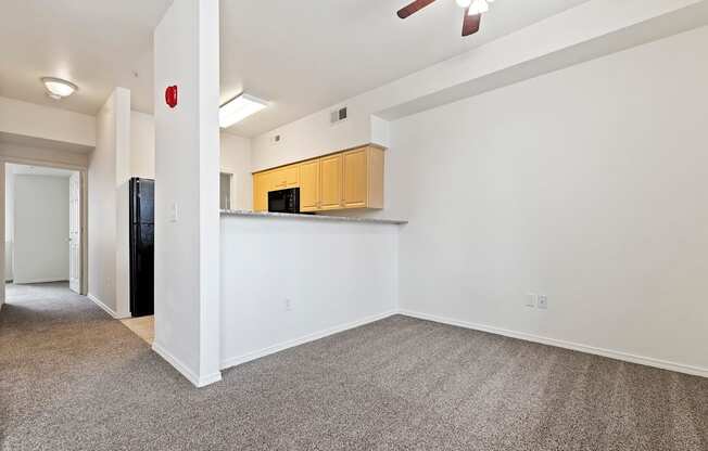 A room with a ceiling fan and a kitchenette.