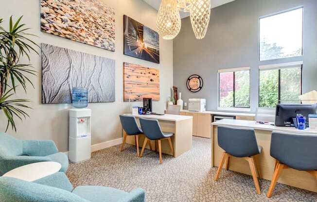 A room with a desk, chairs, and pictures on the wall.