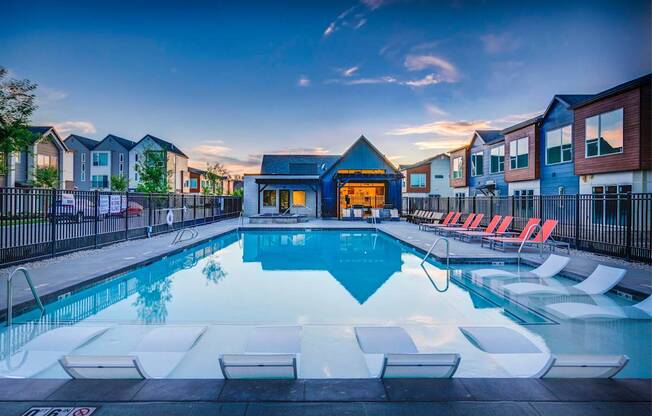 a swimming pool with chairs around it at dusk