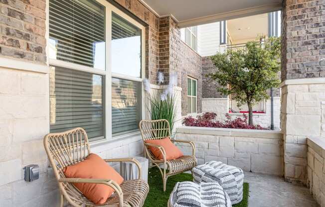 a porch with two chairs and a table and a window