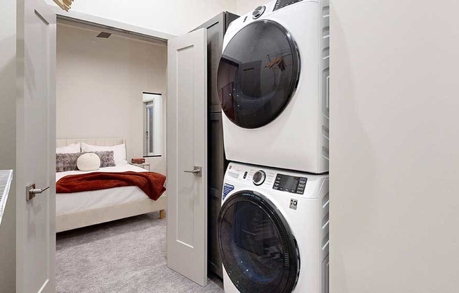a stacked washer and dryer inside a walk-in closet