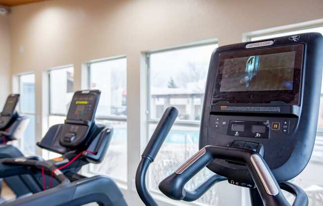 a gym with cardio machines and a large window