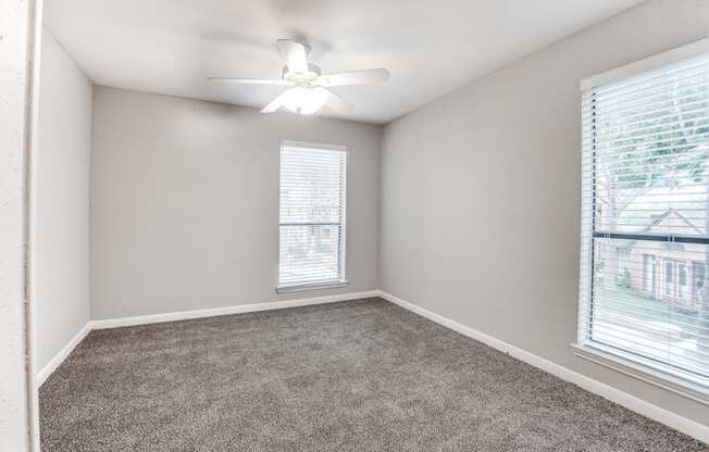 an empty bedroom with a ceiling fan and a window