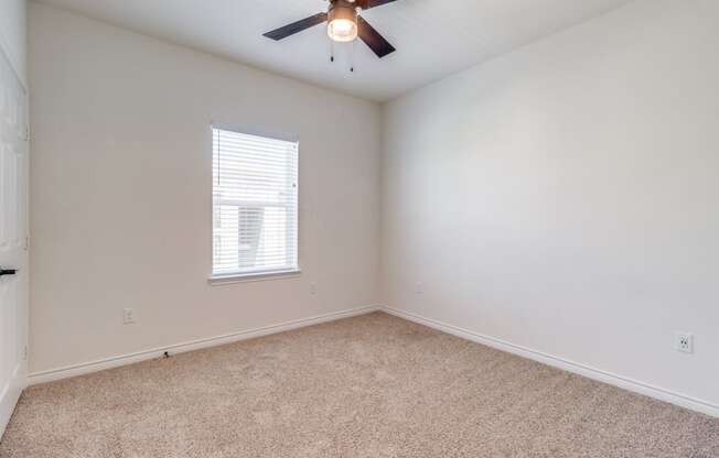 an empty room with a ceiling fan and a window