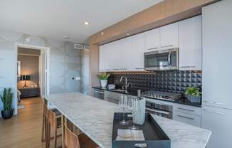 a kitchen with white cabinets and a marble counter top