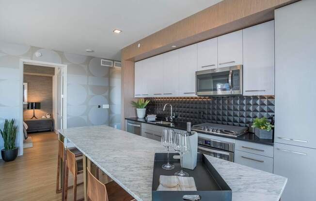 a kitchen with white cabinets and a marble counter top