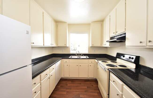 a kitchen with white cabinets and black countertops