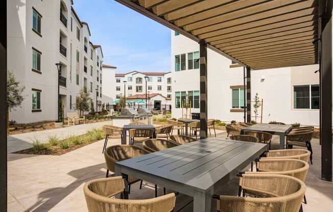 A patio with a table and chairs is surrounded by buildings at Pradera Apartments, California