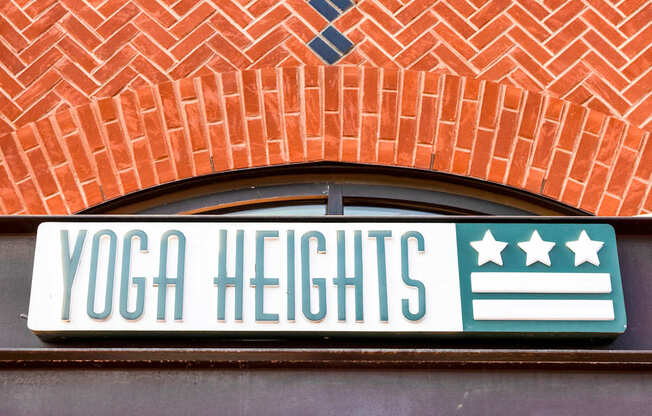 A sign that says Yoga Heights on a brick wall.