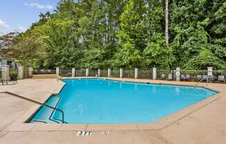 A small pool surrounded by a fence and trees.