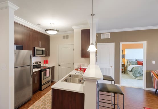 Kitchen with dark cabinets, quartz countertops, vinyl plank floors, stainless steel appliances