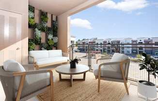 A living room with a couch, chair, and table with a view of a cityscape.