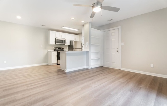 an empty living room and kitchen with a ceiling fan