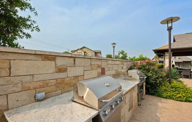 an outdoor kitchen with a stone wall and a grill