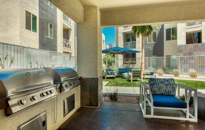 A patio with a grill and a chair with a blue cushion.