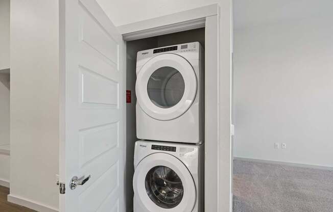 A white door is open to reveal a white washing machine and dryer.
