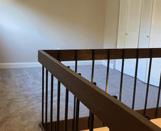 View of loft with grey carpet and wood railings at Silvertree Apartments