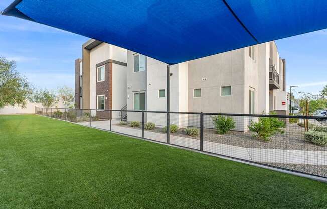 A blue canopy is over a green lawn.