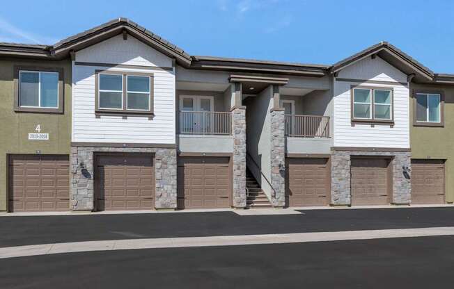 A modern two-story house with stone pillars and garage doors.