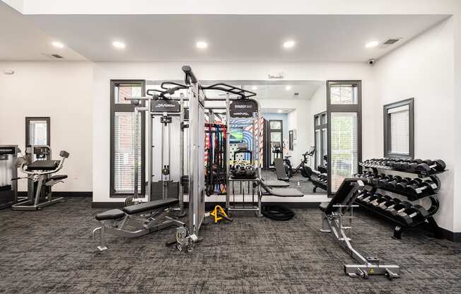 a gym with weights and cardio equipment in a room with windows