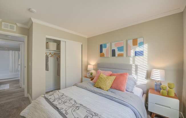 One-Bedroom Apartments in Moreno Valley, CA - Ardella on Chagall - Bedroom with Carpeted Flooring, Bed, Nightstands with Lamps, Cream-Colored Walls, and Large Closet.