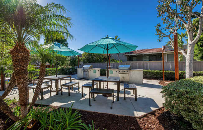 a patio with tables and umbrellas and a grill