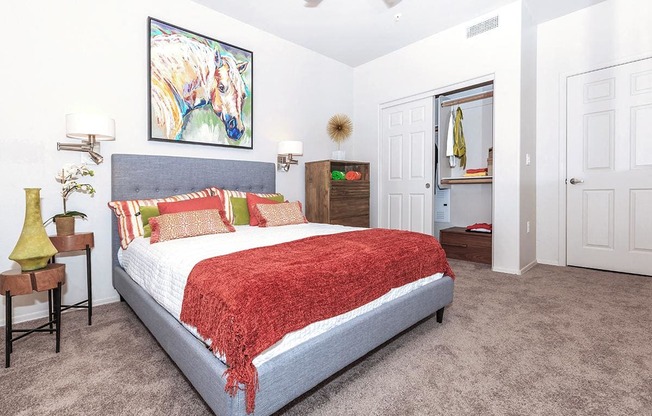 Queen sized Platform bed decorated with bright trendy throw pillows in large bedroom in 1x1 model apartment