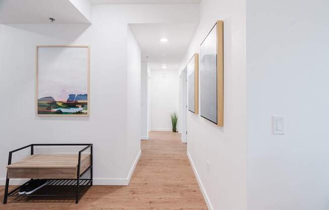 A long hallway with a bench and pictures on the wall.