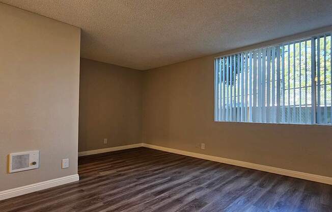 A room with a window and wooden flooring.