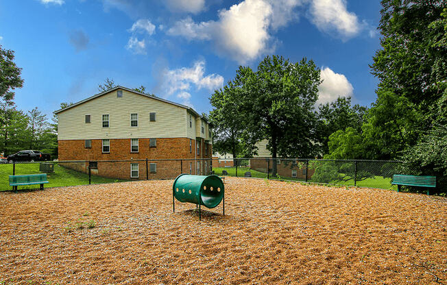 a fenced in dog park with a house in the background