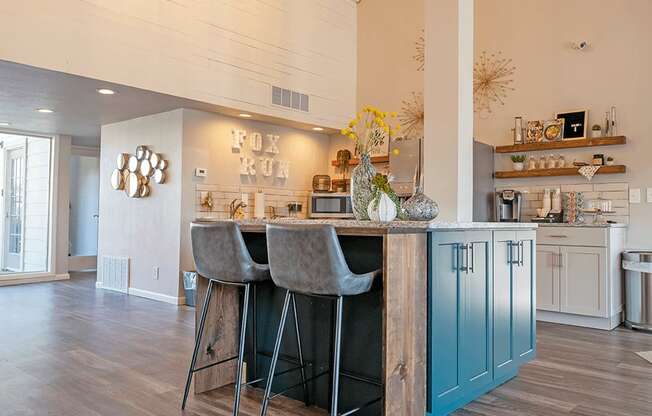 a kitchen with blue cabinets and a bar with two stools