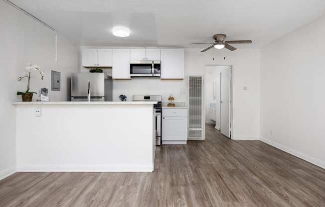 an open kitchen and living room with a counter top and a ceiling fan