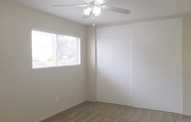 an empty living room with a ceiling fan and a window