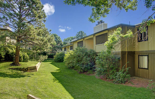 a building with a green lawn and trees in front of it