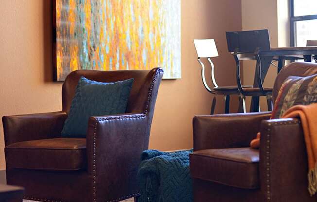 a living room with leather chairs and a painting on the wall