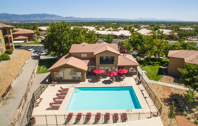 A large house with a pool and a patio with red chairs at West Park Apartments, Albuquerque, 87114