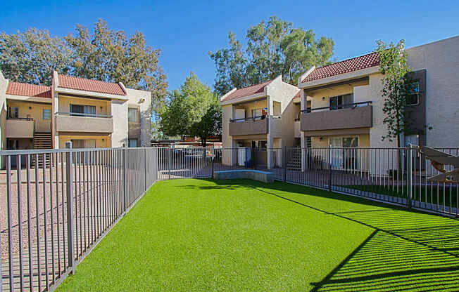 the outlook of a yard with a fence and apartment buildings