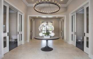 a long hallway with a round table and a large chandelier