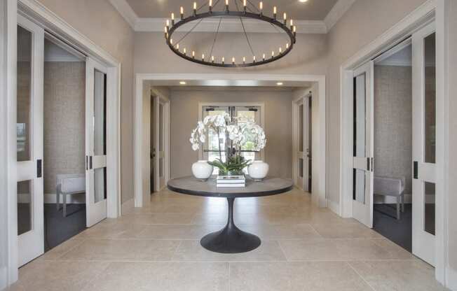 a long hallway with a round table and a large chandelier