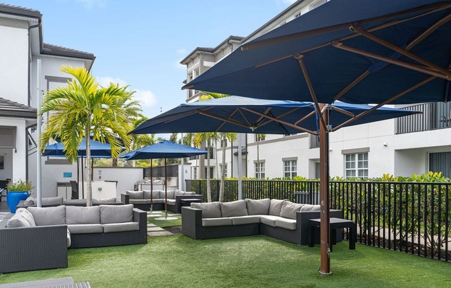 a lounge area with couches and umbrellas on a lawn