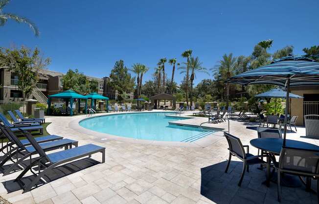A pool area with chairs and umbrellas.