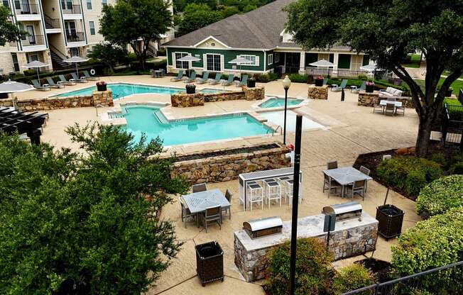 an aerial view of a pool and patio with tables and umbrellas