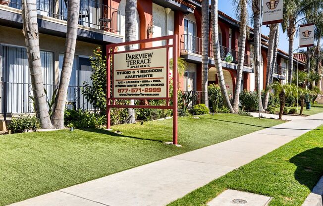 A sign for Parkview Terrace Studios is in front of a building with balconies.
