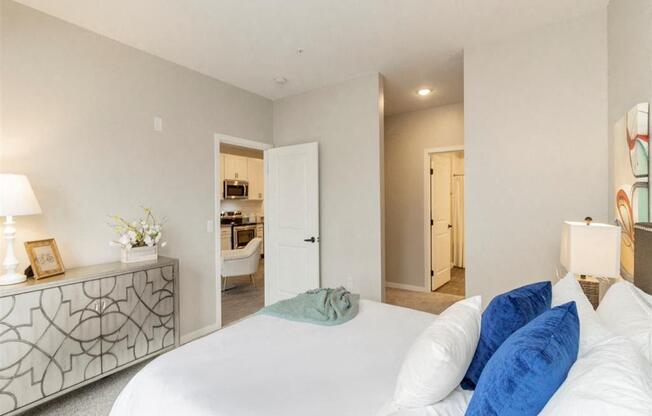 A bedroom with a large bed and a dresser with a lamp on it.
