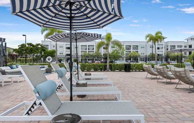 A patio with chairs and umbrellas is in front of a building.