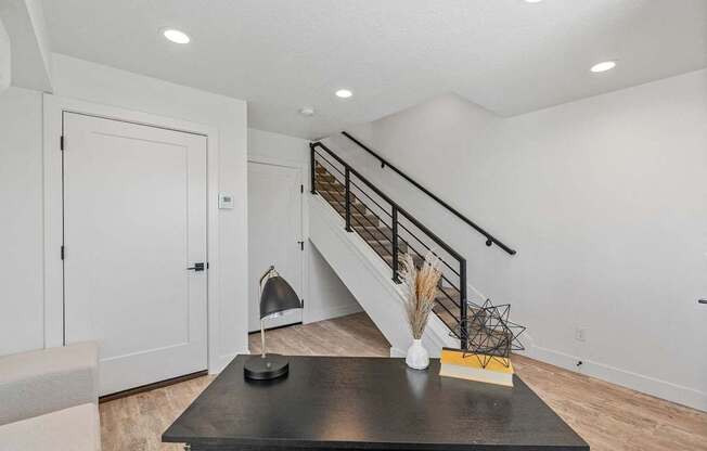 a living room with a staircase and a table and a door