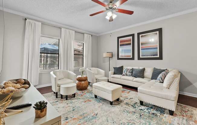 A living room with a white sofa, two chairs, and a rug.
