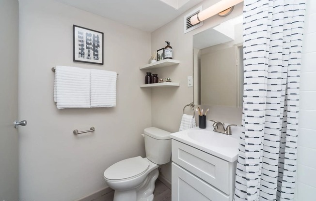 a white bathroom with a shower curtain and a toilet at Archer Tower in Denver, CO