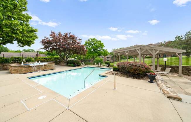 A pool surrounded by a patio and trees.